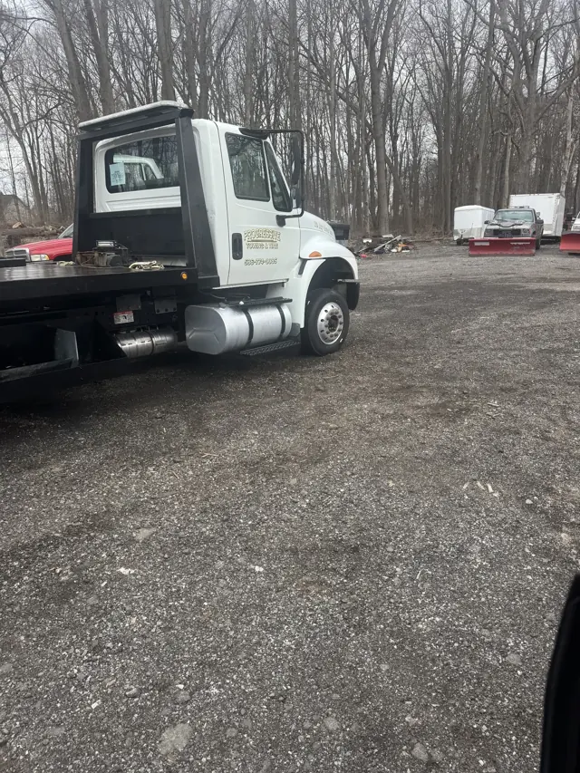 White Progressive Towing and Tire flatbed truck with (586) 744-0085 printed on the cab